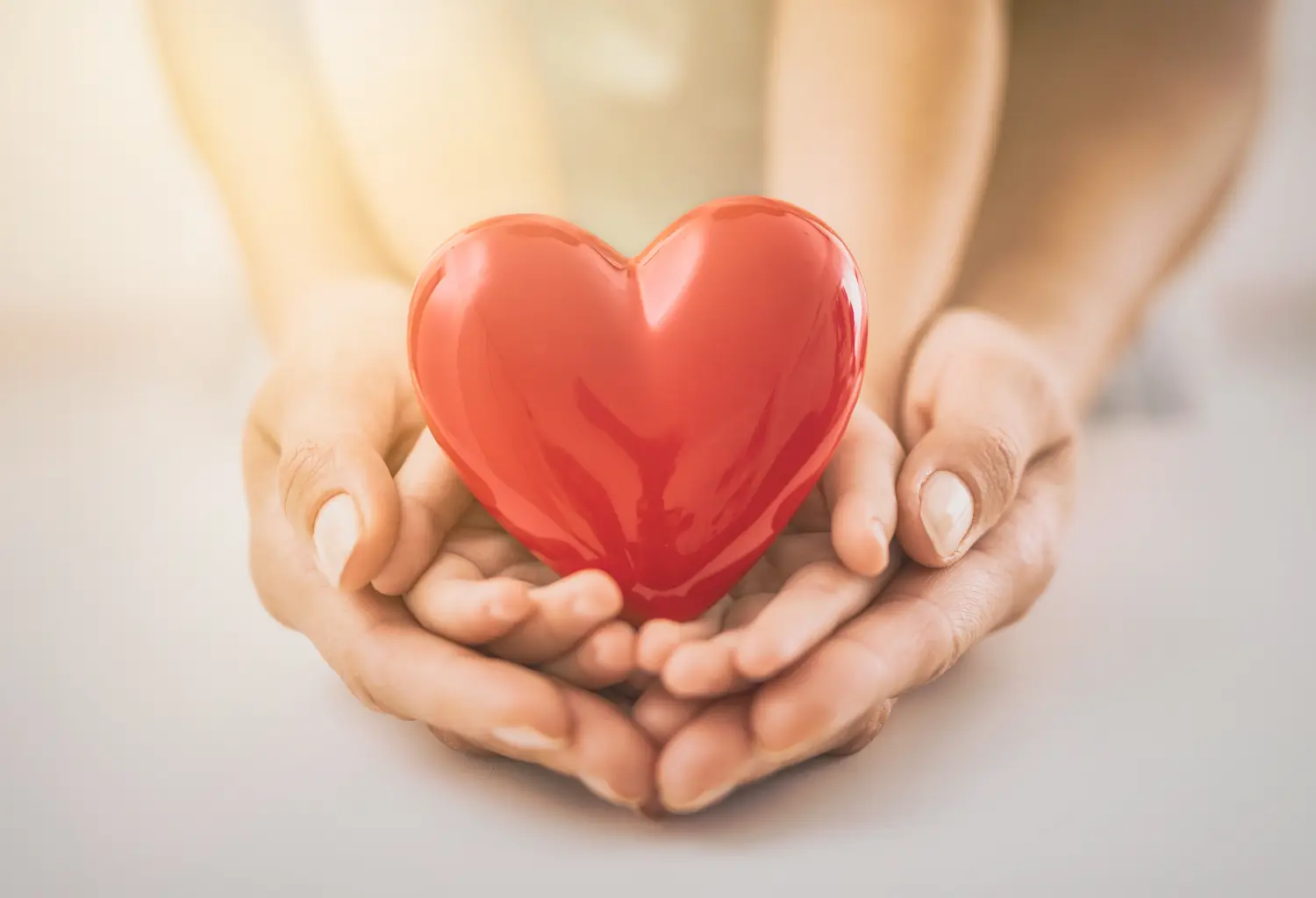 BesserLeben GbR - Intensivpflegedienst -Der Erwachsene und das Kind halten ein rotes Herz.